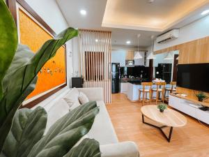 een woonkamer met een witte bank en een grote plant bij 2 Bedrooms Permata Hijau Suites Apartment in Jakarta