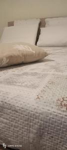 ein Bett mit weißer Bettwäsche und einem Kissen darauf in der Unterkunft B&B LEO'S in Cagliari