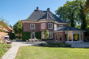 een groot rood bakstenen huis met een veranda en een patio bij Ehemaliges Gutshaus Oevelgönne 