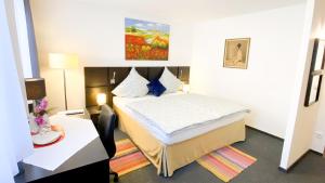 ein Hotelzimmer mit einem Bett, einem Schreibtisch und einem Tisch in der Unterkunft Hotel garni Bad Café Bad Niedernau in Bad Niedernau