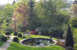 einen Garten mit einem Teich, einer Bank und Bäumen in der Unterkunft Ferien im Königshaus in Möhnesee