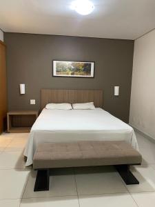 712 - FLAT para temporada em Goiania-proximo ao Parque Areião في غويانيا: غرفة نوم مع سرير أبيض كبير مع مقعد
