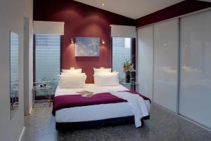 a bedroom with a large bed with red walls at By the Beach B&B Self Contained Apartments in Sanctuary Point