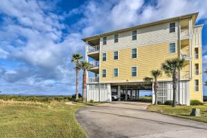 a large yellow building with palm trees next to a road at Driftwood Galveston Resort Escape with Deck and View in Galveston