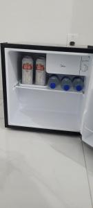 a white refrigerator with four cups and bottles in it at Suítes Guriri in Guriri