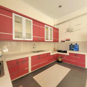 a kitchen with red cabinets and a sink at Mahakam Guest House in Padang