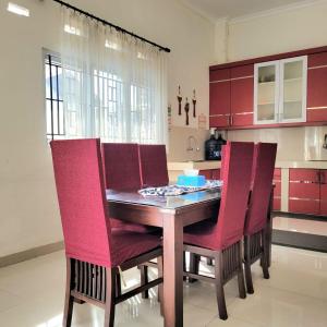 a kitchen with a wooden table and red chairs at Mahakam Guest House in Padang