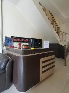 a lobby with a bar with a couch and stairs at Mahakam Guest House in Padang