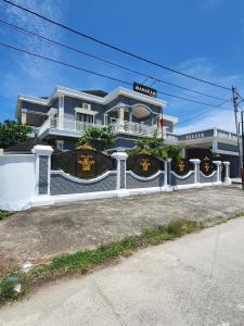 a house with a white fence in front of it at Mahakam Guest House in Padang