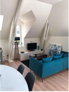 a living room with a blue couch and a tv at Appartement vue bassin 2 chambres in Arcachon