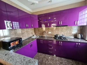 a purple kitchen with purple cabinets and a stove at Gricko in Tbilisi City