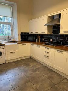 a kitchen with white cabinets and a tile floor at Victorian 3 BR main door flat, King size beds , large rooms in Glasgow