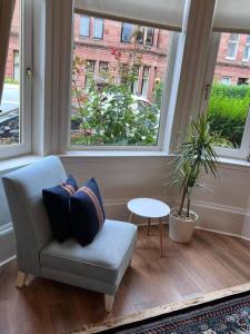 a living room with a chair and a table and windows at Victorian 3 BR main door flat, King size beds , large rooms in Glasgow