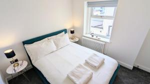 a bedroom with a white bed and a window at Ocean Pearl Apartment by Seaside Llandudno in Llandudno