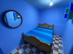 a blue room with a bed and a mirror at Dar Lazrak in Chefchaouen