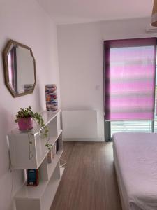 Cette chambre blanche comprend un lit et un miroir. dans l'établissement Joli appartement coquet et cosy, à Royan