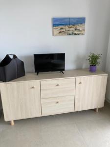 un centro de entretenimiento de madera con TV de pantalla plana. en Joli appartement coquet et cosy, en Royan