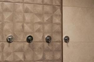 a tiled shower with two knobs on a wall at Apartmán Jesienka, Hillside in Dolný Kubín