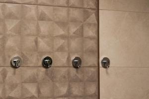 a tiled shower with two knobs on a wall at Apartmán Jesienka, Hillside in Dolný Kubín +84 photos