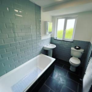a bathroom with a tub and a toilet and a sink at Mary Cottage, Braunton, Devon in Braunton