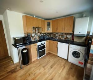 cocina con armarios de madera, lavadora y secadora en Mary Cottage, Braunton, Devon en Braunton