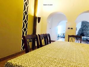 a table and chairs in a room with a yellow wall at Nubian Holiday House Aswan in Aswan