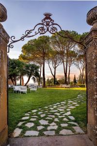 ein offenes Tor zu einem Park mit Bänken im Gras in der Unterkunft Palazzo Massaini - La Pieve in Pienza