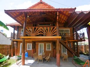 a house with a wooden roof and a table and chairs at Xô Xôn Homestay in Kon Rơbang