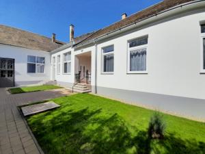 a white house with a green lawn at Déri Kert Apartmanház A in Baja