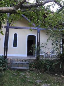 a small white house with a black door at Casa no paraíso ecológico da Ilha Grande in Abraão