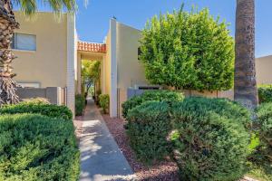 einen Garten mit Büschen, einem Gebäude und einer Palme in der Unterkunft Charming Condo in the Heart of Scottsdale in Scottsdale