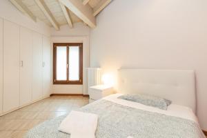 ein weißes Schlafzimmer mit einem Bett und einem Fenster in der Unterkunft Trilocale Rua Sovera 85 - F&L Aparment in Brescia