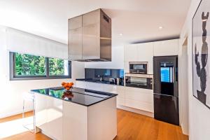 a kitchen with white cabinets and a black refrigerator at Villa Panoramica by Esteva Emerald Stay in Cielo de Bonaire 