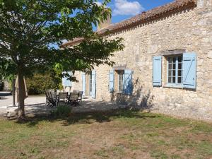 un edificio in pietra con due panche e un albero di Gite l'Herbier a Conne-de-Labarde