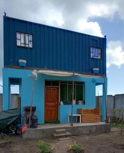 una casa azul con una puerta roja delante de ella en Beach House in Kigamboni Dar es Salaam en Dar es Salaam