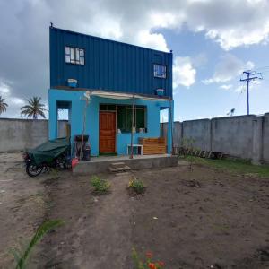 una casa azul con una motocicleta estacionada frente a ella en Beach House in Kigamboni Dar es Salaam en Dar es Salaam