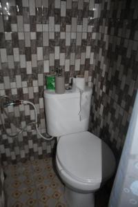 a bathroom with a white toilet in a tile wall at Beach House in Kigamboni Dar es Salaam in Dar es Salaam