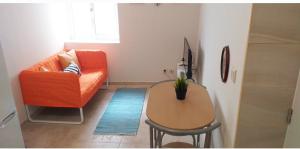 uma sala de estar com um sofá laranja e uma mesa em Made in You - Oporto Rooms no Porto