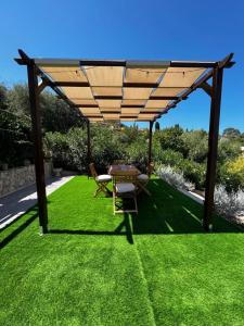 a pergola with a table and chairs on a lawn at Pater Meus Suites in Cefalù