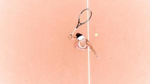 uma mulher a bater numa bola de ténis com uma raquete em Grande Hotel Termas de Araxá em Araxá