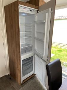 an empty refrigerator with its door open and a chair at Adams Caravan Holidays in Morecambe