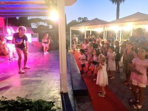 un grupo de niños parados en un escenario de una fiesta en Hotel La Buca Del Gatto en Marina di Cecina