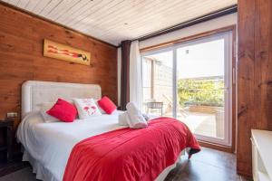 a bedroom with a bed with a red blanket and a window at Pichilemu Apart Hotel in Pichilemu