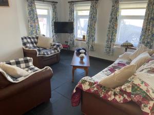 a living room with two couches and a tv at Tranquil 2 Bedroom Cottage With Hot Tub Sea View Teach Cha in Sessiagh