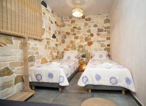 duas camas num quarto com uma parede de pedra em Markos Home em Koutsounári