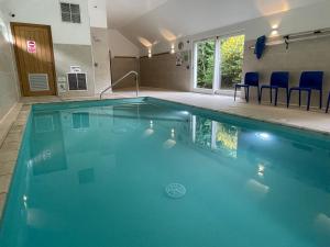 a swimming pool with blue water in a building at Swandown, 3 Blackdown in Chard