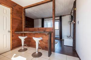 a room with a wooden wall and two white stools at Pichilemu Apart Hotel in Pichilemu