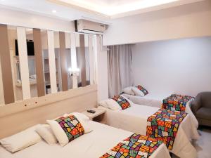 a hotel room with two beds and a mirror at Hotel Rediadri - Capão da Canoa in Capão da Canoa