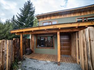 a house with a wooden deck next to a fence at Cielo Sur Balsas Loft in Villa La Angostura