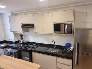 a kitchen with white cabinets and a stainless steel refrigerator at Apartamento em Condomínio Frente Mar Barra Velha-SC in Barra Velha